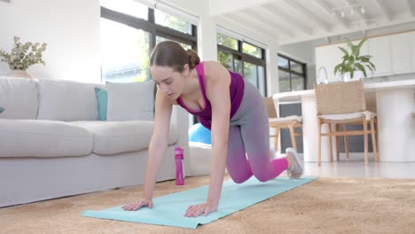 Focused-caucasian-woman-exercising-at-home-on-mat-in-slow-motion