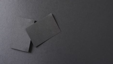 Overhead-view-of-blank-black-business-cards-on-black-background,-copy-space,-slow-motion