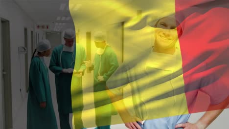Animation-of-flag-of-belgium-waving-over-smiling-caucasian-surgeon-standing-in-corridor-of-hospital