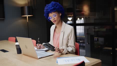 Portrait-of-happy-biracial-businesswoman-with-blue-afro-using-smartphone,-slow-motion