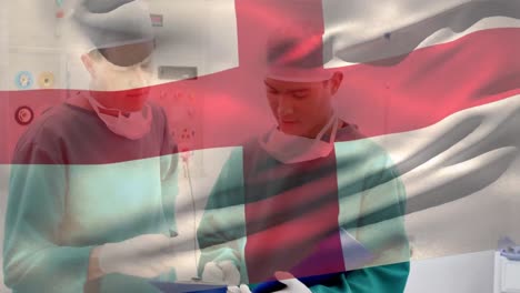 Animation-Der-Englischen-Flagge-über-Verschiedene-Chirurgen,-Die-Patientenberichte-Im-Operationssaal-Diskutieren