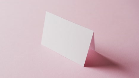 Close-up-of-two-blank-white-business-cards-on-pink-background,-copy-space,-slow-motion