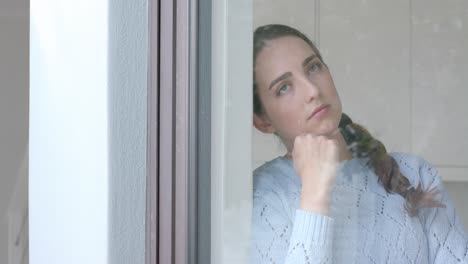 Nachdenkliche-Kaukasische-Frau,-Die-In-Zeitlupe-Ihr-Kinn-Am-Fenster-Berührt
