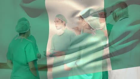 Animation-of-flag-of-nigeria-waving-over-diverse-surgeons-discussing-in-hospital