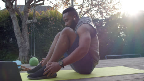 Focused-african-american-man-fitness-training-doing-crunches-on-deck-in-sunny-garden,-slow-motion