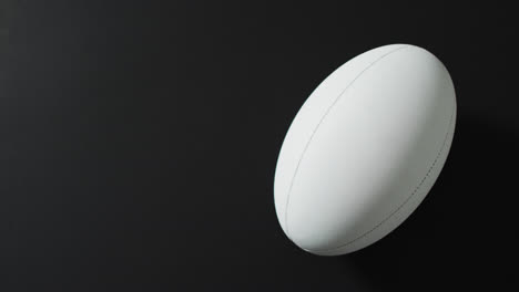 Weißer-Rugbyball-Auf-Schwarzem-Hintergrund-Mit-Kopierraum,-Zeitlupe
