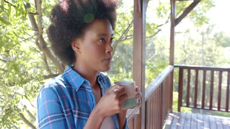 Fröhliche-Afroamerikanische-Frau-Trinkt-Tee-Auf-Der-Sonnigen-Terrasse,-In-Zeitlupe