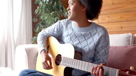 Glückliche-Afroamerikanische-Frau,-Die-Im-Wohnzimmer-Gitarre-Spielt,-In-Zeitlupe