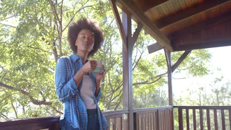 Feliz-Mujer-Afroamericana-Bebiendo-Té-En-Una-Terraza-Soleada,-En-Cámara-Lenta