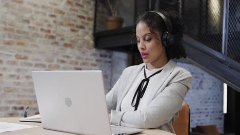 Biracial-casual-businesswoman-making-video-call-using-laptop-in-office-lounge,-slow-motion