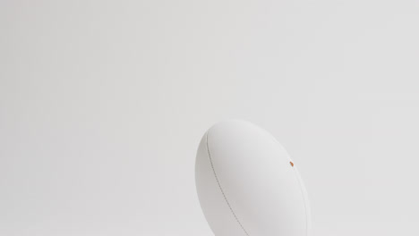 White-rugby-ball-on-kicking-tee-on-white-background-with-copy-space,-slow-motion