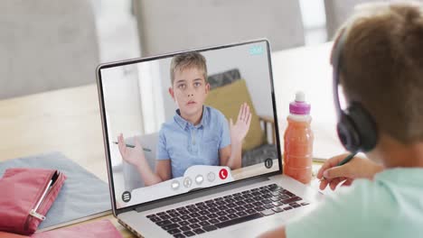 Caucasian-boy-using-laptop-for-video-call-with-caucasian-school-friend-on-screen