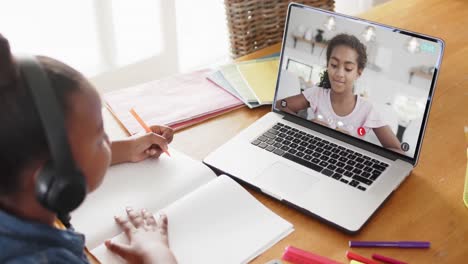 African-american-girl-using-laptop-for-video-call-with-biracial-school-friend-on-screen