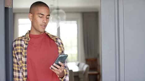 Hombre-Birracial-Feliz-Usando-Un-Teléfono-Inteligente-En-Casa,-Cámara-Lenta