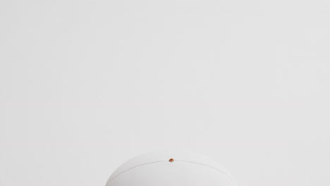 White-rugby-ball-on-white-background-with-copy-space,-slow-motion