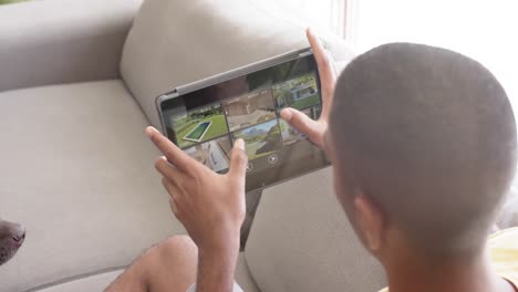Biracial-man-using-tablet-with-home-security-camera-views-on-screen,-slow-motion