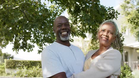 Portrait-of-happy-african-american-senior-couple-embracing-in-sunny-garden,-slow-motion