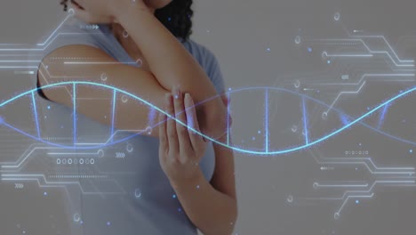 Animation-Von-DNA-Strängen-Und-Netzwerkdiagrammen-über-Dem-Mittelteil-Einer-Biracial-Frau,-Die-Den-Ellbogen-Hält