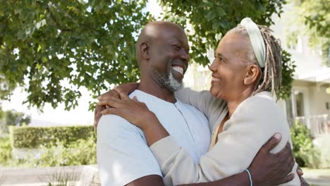 Porträt-Eines-Glücklichen-Afroamerikanischen-Seniorenpaares,-Das-Sich-Im-Sonnigen-Garten-Umarmt,-Zeitlupe
