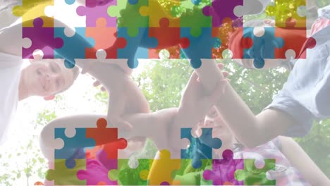 Animation-of-multicolored-puzzle-pieces,-diverse-children-holding-hands-and-forming-abstract-symbol