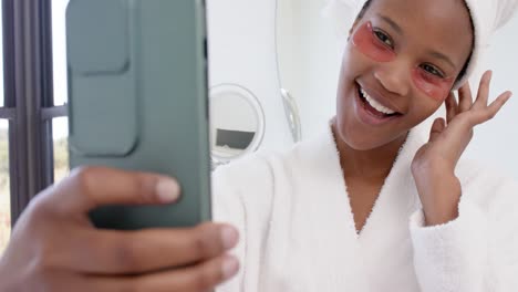 Happy-biracial-woman-with-under-eye-patches-taking-selfie-with-smartphone,-slow-motion