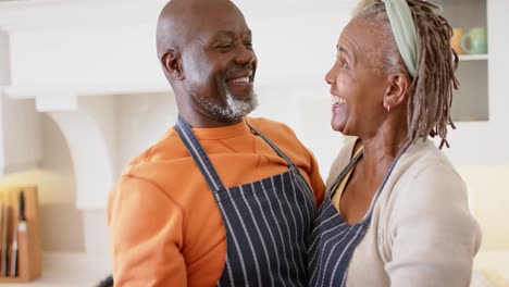 Fröhliches-Afroamerikanisches-Seniorenpaar-In-Schürzen,-Das-In-Der-Küche-Tanzt,-Zeitlupe