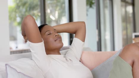 Glückliche-Afroamerikanische-Frau-Mit-Geschlossenen-Augen,-Auf-Dem-Sofa-Sitzend-Und-Entspannend,-Zeitlupe