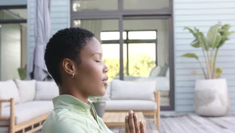 Focused-biracial-woman-practicing-yoga-and-meditating-in-garden,-slow-motion