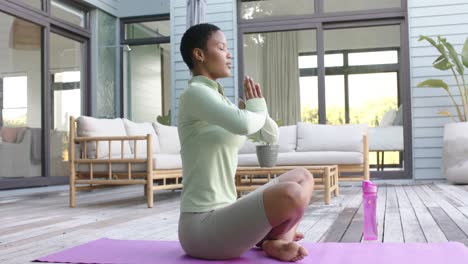 Mujer-Birracial-Enfocada-Practicando-Yoga-Y-Meditando-En-El-Jardín,-Cámara-Lenta