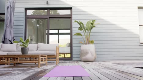 General-view-of-terrace-with-sofa,-plants-and-yoga-mat-on-floor,-slow-motion