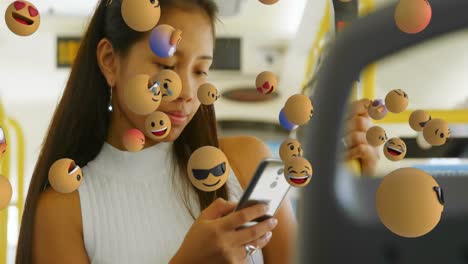 Animation-of-multiple-emoticons-over-asian-woman-using-cellphone-while-travelling-on-bus