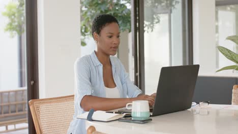 Mujer-Afroamericana-Sentada-En-La-Mesa-Y-Usando-Una-Computadora-Portátil,-Cámara-Lenta