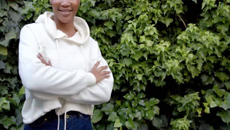 Midsection-of-african-american-woman-in-white-hooded-sweatshirt-in-garden,-copy-space,-slow-motion