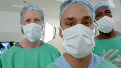 Retrato-De-Diversos-Cirujanos-Masculinos-Usando-Máscaras-Faciales-En-Quirófano,-Cámara-Lenta