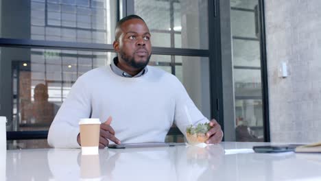 African-american-casual-businessman-using-tablet-and-eating-in-office-meeting-room,-slow-motion