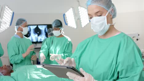 Portrait-of-caucasian-male-surgeon-wearing-surgical-gown,-using-tablet,-slow-motion