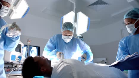 Verschiedene-Chirurgen-Verwenden-Einen-Defibrillator-Am-Patienten-Im-Operationssaal,-Zeitlupe