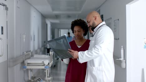 Diverse-doctors-discussing-work-and-looking-at-x-ray-scans-in-corridor,-slow-motion