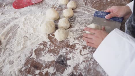 Asian-female-baker-working-in-bakery-kitchen,-making-rolls-from-dough-in-slow-motion