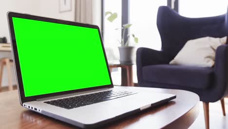 Composition-of-laptop-with-green-screen-on-table-at-home