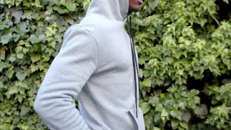 Midsection-of-african-american-man-wearing-grey-hooded-sweatshirt-in-garden,-slow-motion,-copy-space