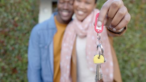 Portrait-of-happy-african-american-couple-standing-outside-house-holding-keys,-slow-motion