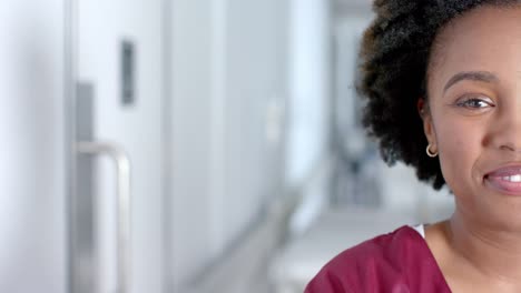 Portrait-of-happy-african-american-female-doctor-smiling-in-corridor,-copy-space,-slow-motion