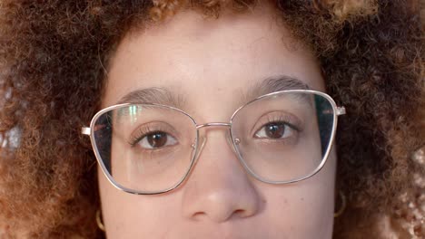 Portrait-close-up-of-biracial-casual-businesswoman-in-glasses-opening-eyes-and-smiling,-slow-motion