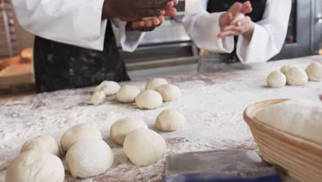 Diverse-bakers-working-in-bakery-kitchen,-making-rolls-from-dough-in-slow-motion