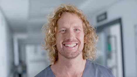 Portrait-of-happy-caucasian-male-doctor-with-curly-hair,-smiling,-slow-motion