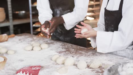 Happy-diverse-bakers-working-in-bakery-kitchen,-making-rolls-from-dough-in-slow-motion