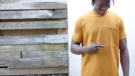 Happy-african-american-man-wearing-yellow-t-shirt-pointing-to-pocket,-slow-motion,-copy-space