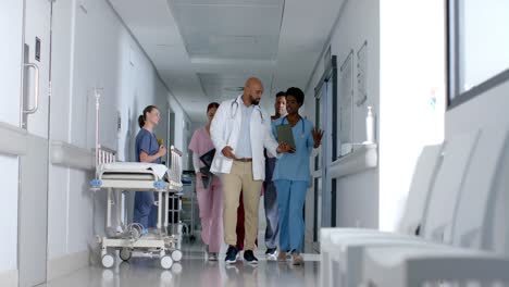 Diverse-doctors-using-tablet-and-walking-in-corridor-at-hospital,-slow-motion