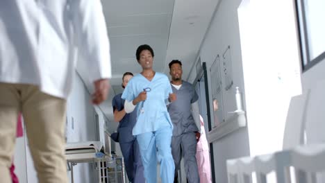 Diverse-doctors-running-in-corridor-at-hospital,-slow-motion